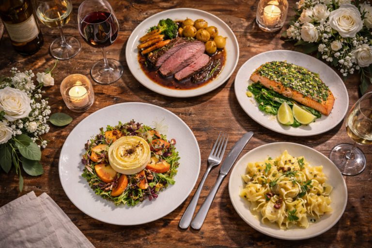 Elegantes 4-Gang Menü mit Ziegenkäse, Roastbeef, Lachs und Pasta auf rustikalem Holztisch